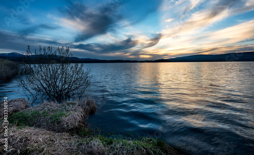 Magical Sunset over the lake with a beautiful reflection on the water. Serene lake in blue hour. Nature landscape photo