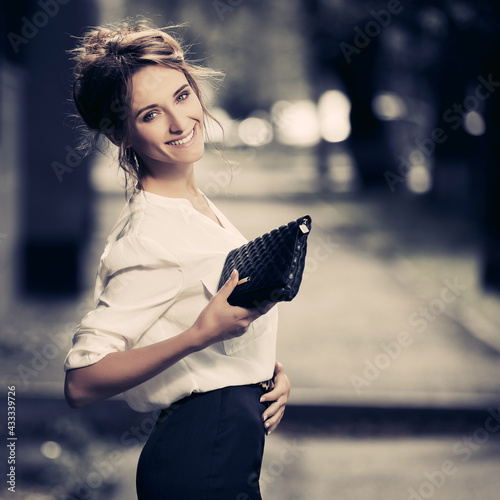 Young fashion business woman in white shirt with clutch bag