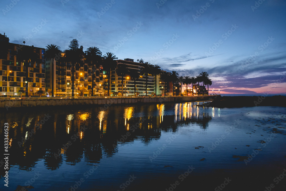 Beautiful panoramic view of the Marga Marga river, the ocean, palms, buildings with lights and reflections at the sunset, Viña del Mar, Chile
