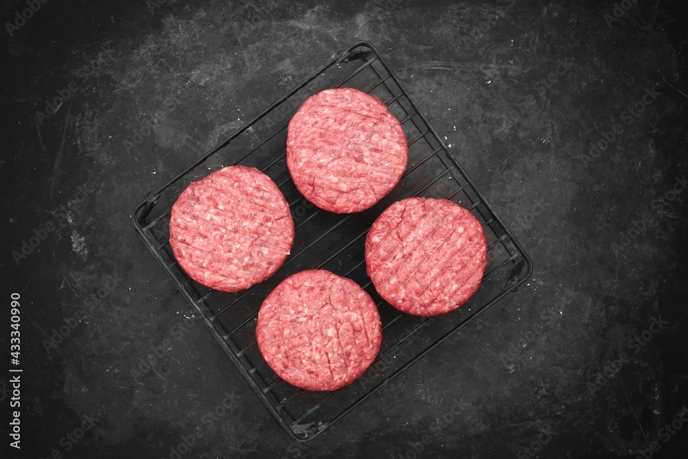 Grill Barbecue Grate with Raw Beef Hamburger Patties. Ground Beef Patties for Grilling and Roasting. Raw Minced Steak Burgers from Beef Meat on Black Background. Burger Cutlets On Paper And Grate. Grill Barbecue Grate with Raw Beef Hamburger Patties. Ground Beef Patties for Grilling and Roasting. Raw Minced Steak Burgers from Beef Meat on Black Background. Burger Cutlets On Paper And Grate.