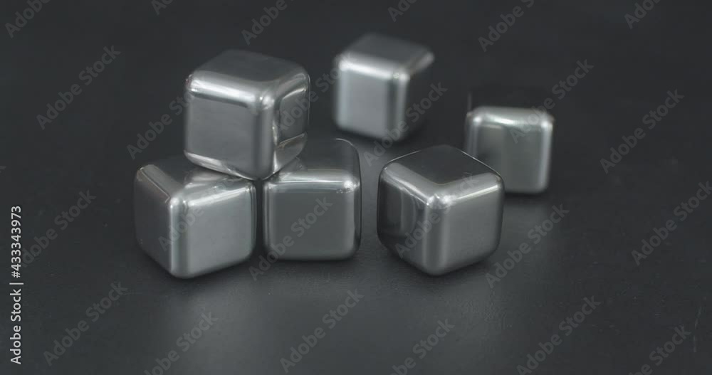 Light catches 6 reusable stainless steel whiskey Ice Cubes against a black black ground. Light catches 6 reusable stainless steel whiskey Ice Cubes against a black black ground.