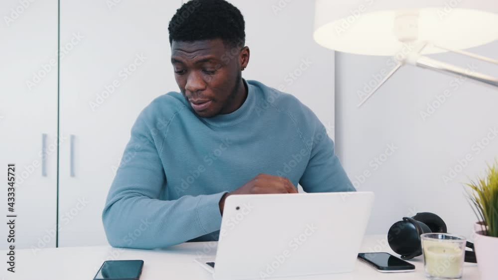 African American black man sitting at the table in front of a laptop ...