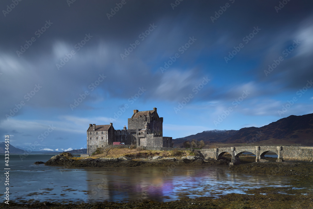 Scottish castle on lake with reflections in the water and cloudy sky. Eilean Donan