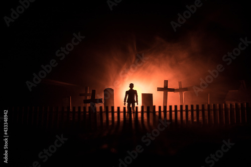 Scary view of zombies at cemetery dead tree, moon, church and spooky cloudy sky with fog, Horror Halloween concept with glowing pumpkin. Selective focus