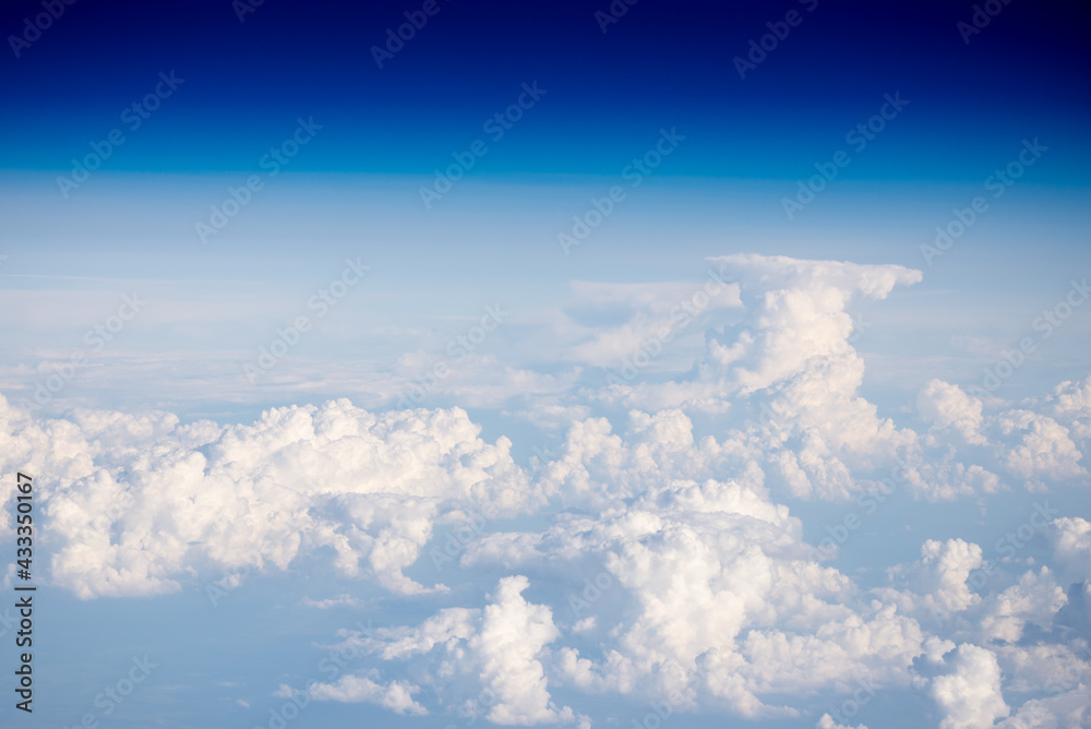 Clouds from a height of ten kilometers. Sea of clouds from the plane window. Blue sky and white clouds. The Heavenly World of White Silence