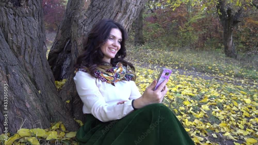 Slow Motion Beautiful smiling woman using mobile phone in autumn park Slow Motion Beautiful smiling woman using mobile phone in autumn park