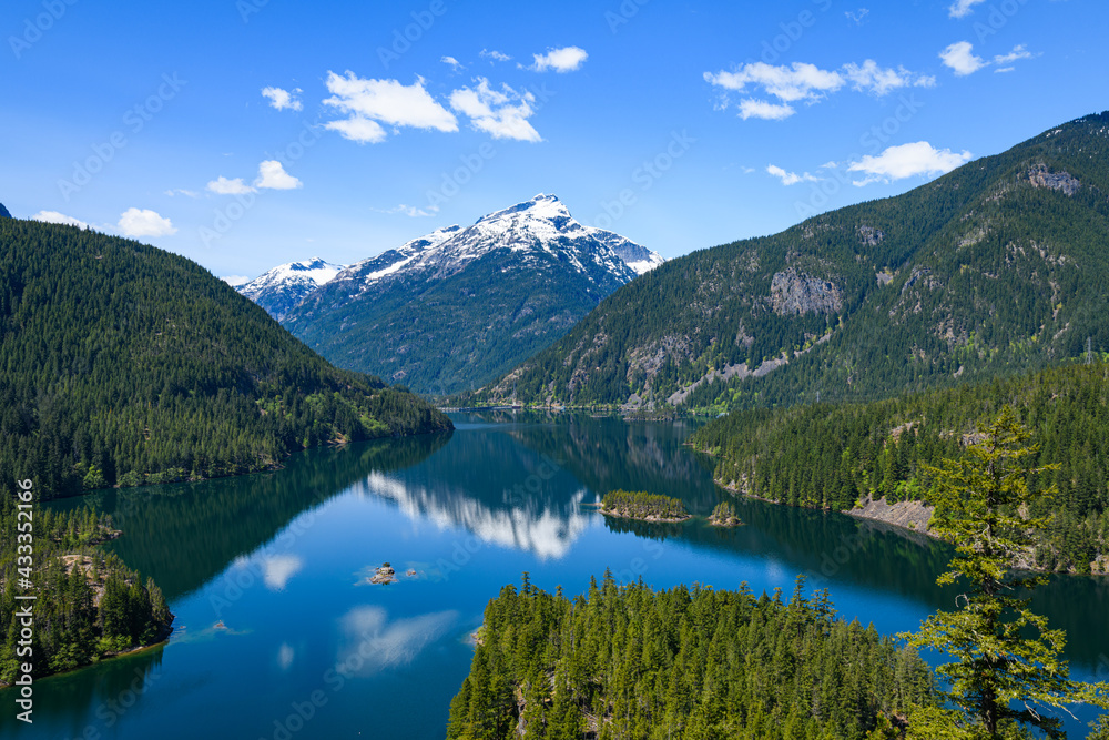 Diablo Lake in the North Cascades of Washington State under a blue sky with a beautiful reflection of   Davis Peak mountain in the fresh water