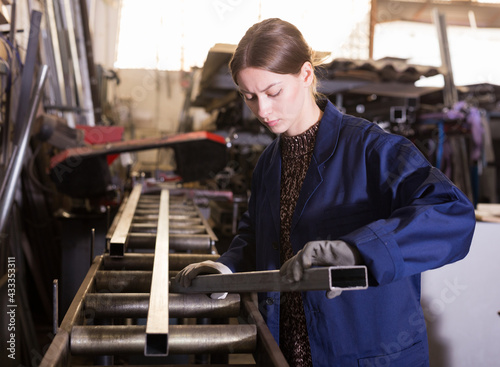 Qualified focused workwoman inspecting shape of steel stocks in metal cutting workshop....