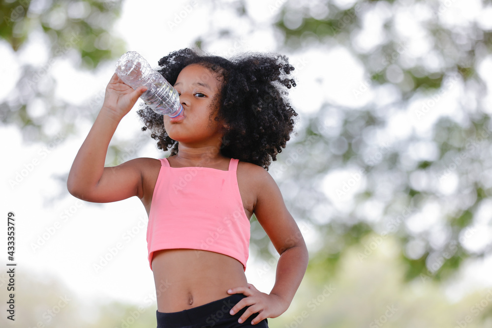 Little girl drinking water from plastic bottles after exercise at outdoor Little girl drinking water from plastic bottles after exercise at outdoor