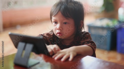 Little cute beautiful girl, Asian people sit and watch their smartphone very focused and intently. The idea of children being too addicted to smartphones in watching cartoons and playing games