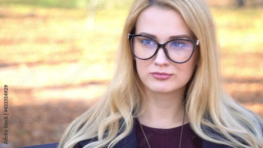 4K A young woman in large black glasses is looking at the camera 4K A young woman in large black glasses is looking at the camera
