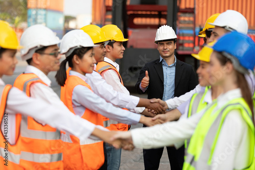 warehouse boss engineer thumbs up pose and factory workers shaking hands for congratulations in containers warehouse storage