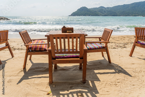 Wooden table and chairs in empty beach cafe next to sea water. Close up  Thailand