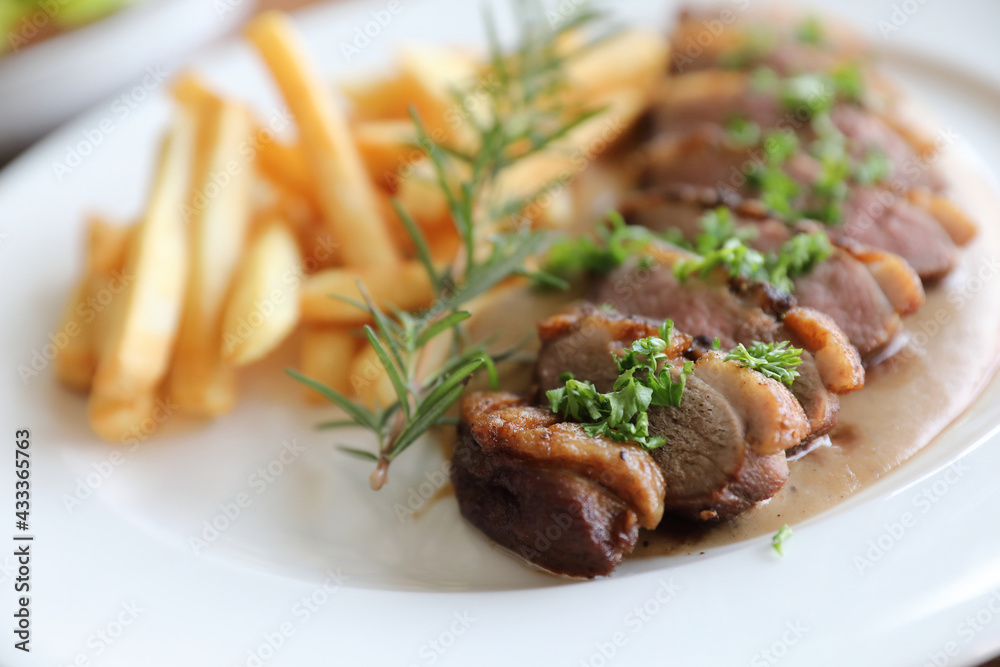 Duck magret confit with chips on wood table Duck magret confit with chips on wood table
