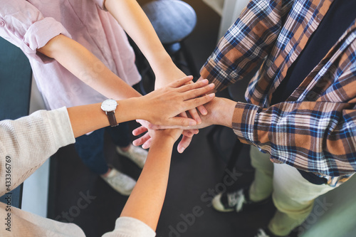 Closeup image of business team standing and joining their hands together in office