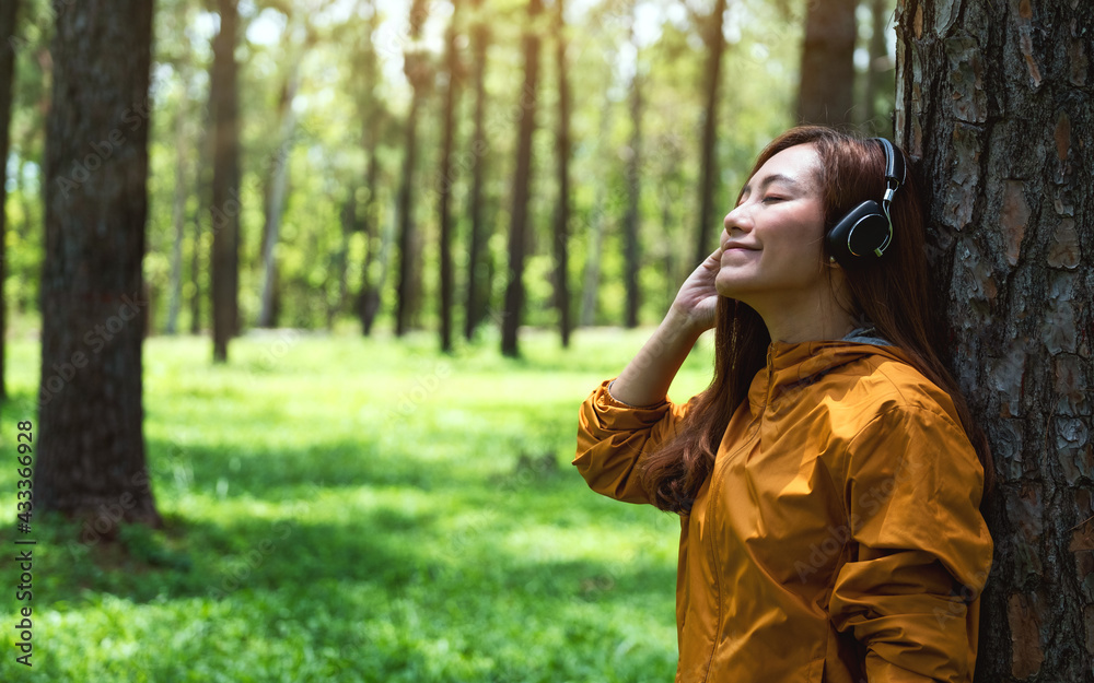 Portrait image of a beautiful young asian woman enjoy listening to music with headphone in the park Portrait image of a beautiful young asian woman enjoy listening to music with headphone in the park