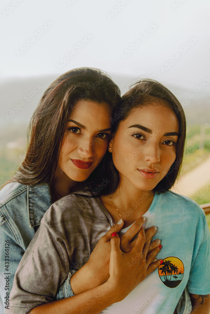 Retrato de pareja de lesbianas peruanas abrazándose y entrelazando las manos en la selva peruana