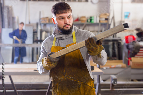 Portrait of man worker in uniform working with metal beams in workshop