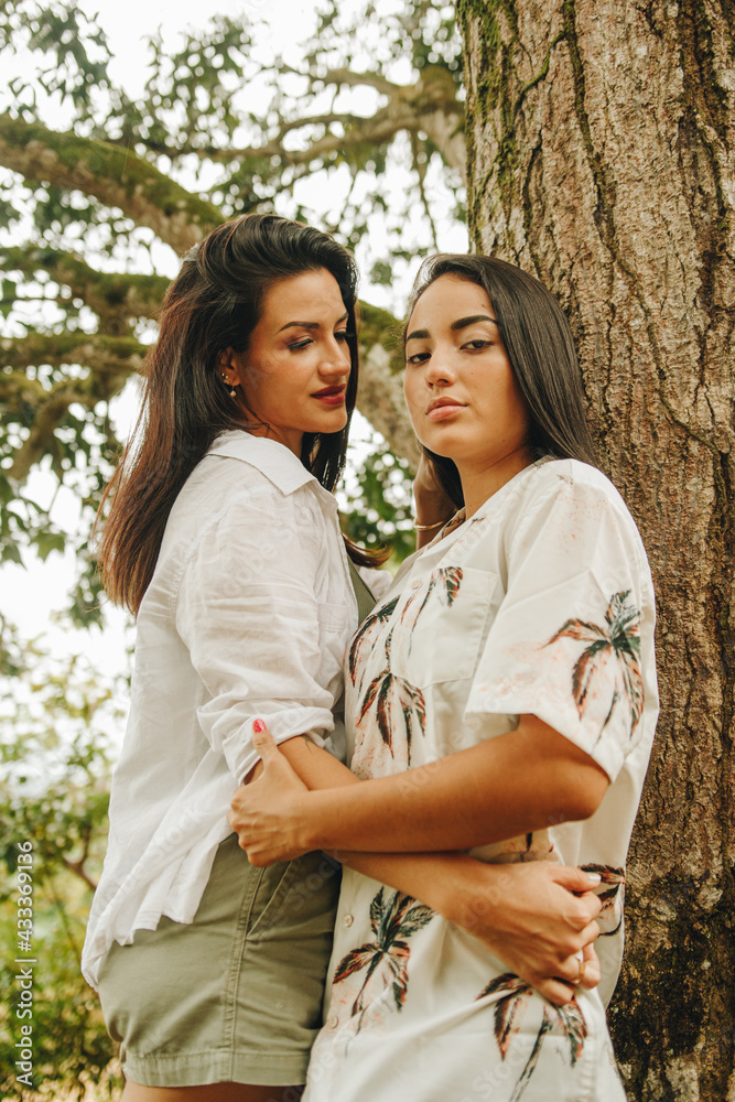 Retrato de pareja de lesbianas posando al lado de un árbol Retrato de pareja de lesbianas posando al lado de un árbol