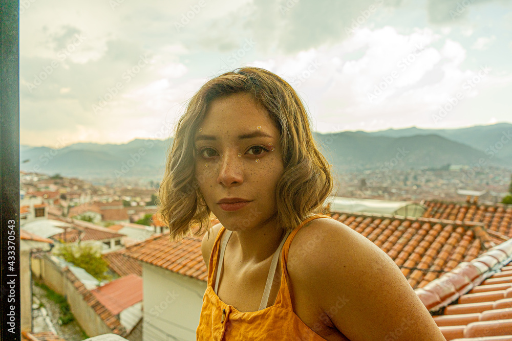 Retrato a contraluz de mujer joven bisexual con la vista de la ciudad de Cusco 