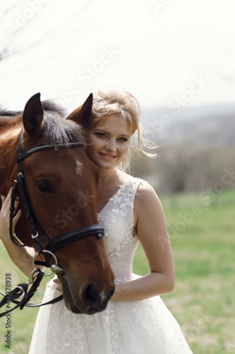 An attractive bride next to a horse. Wedding photography with a horse at sunset.
