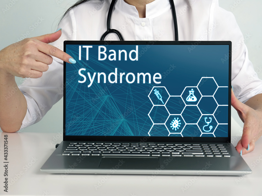 IT Band Syndrome inscription on the screen. Close up Cardiologist hands holding black laptop. IT Band Syndrome inscription on the screen. Close up Cardiologist hands holding black laptop.