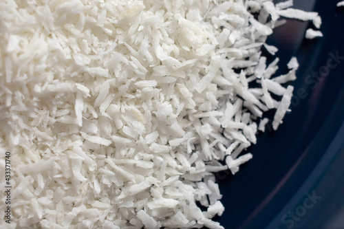 A top down closeup view of a plate of shredded coconut flakes.