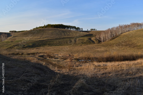 Beautiful landscape in early spring. View of hilly terrain  trees  country road