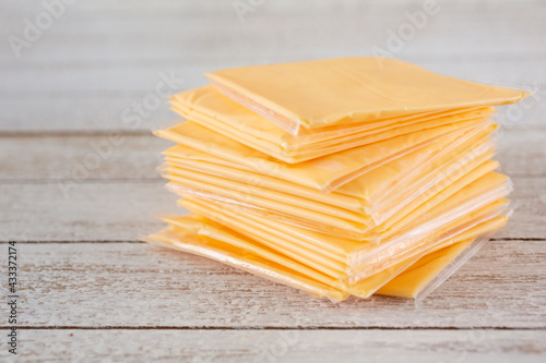A closeup view a stack of processed cheese slices, individually wrapped in plastic.