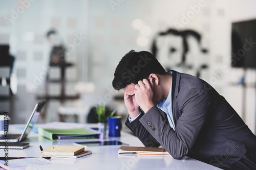 Фотография Stressful young businessman holding his heads and feeling stressed about work