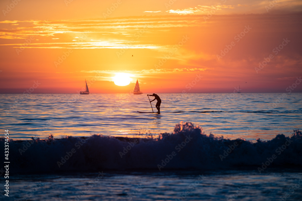 Silhouette of paddle board. Tropical beach sea ocean with sunset or sunrise for summer travel vacation. Ocean seascape.