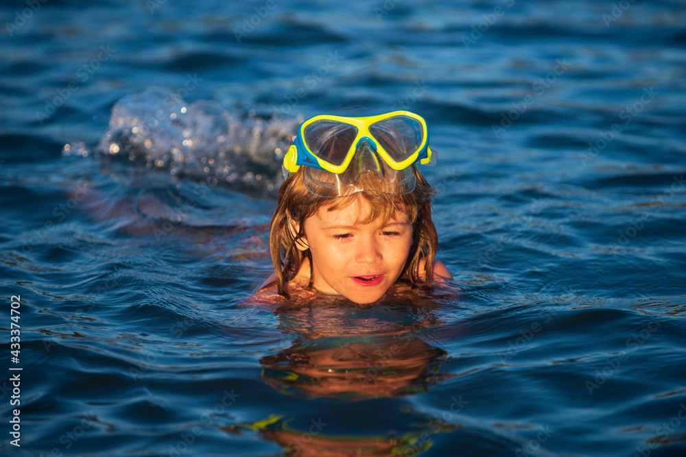 Fototapeta premium Boy swim on the beach on summer holidays. Happy kids swimming in the water. Little boy swimming in ocean or sea.