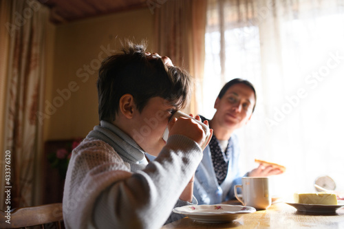 Portrait of poor small girl with mother eating indoors at home  poverty concept.