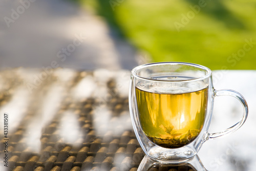 Cup with herbal tea on the table, gazebo in the backyard