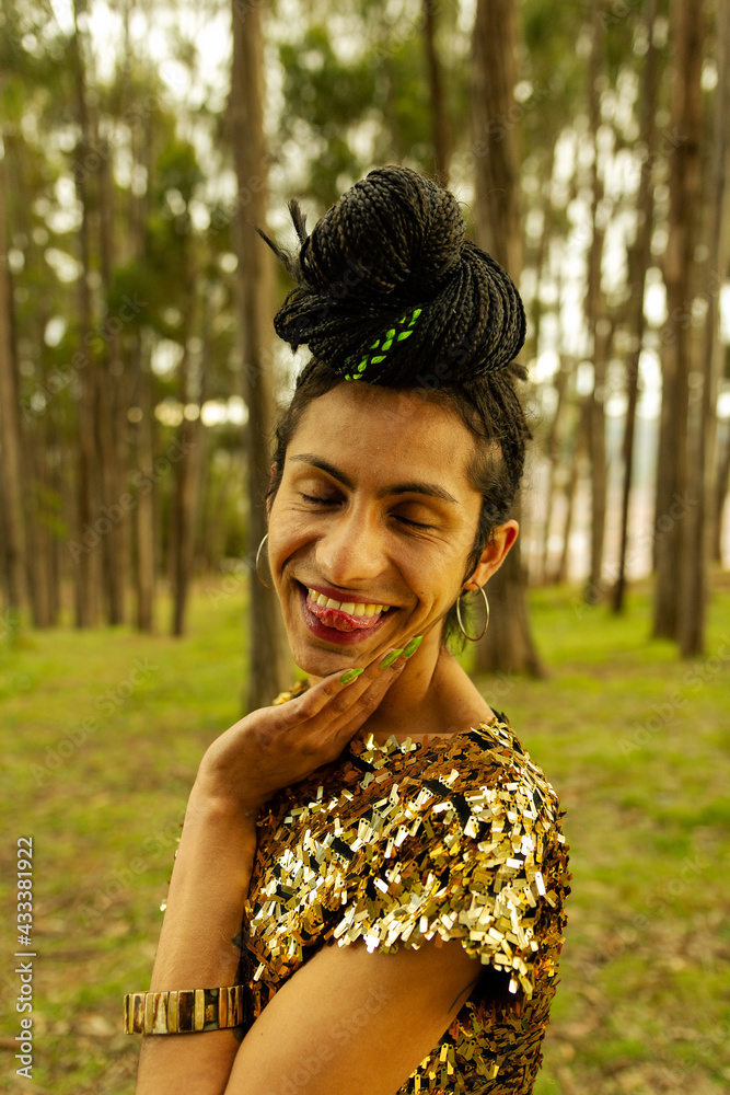 Retrato de mujer transgénero con vestido dorado y trenzas haciendo una mueca graciosa en el bosque Retrato de mujer transgénero con vestido dorado y trenzas haciendo una mueca graciosa en el bosque