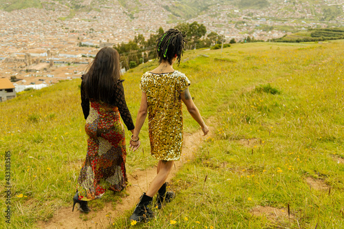 Mujeres transgénero caminando en bajada cogiéndose las manos  en el campo de flores  photo