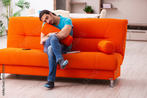 Young male student sitting on the orange sofa
