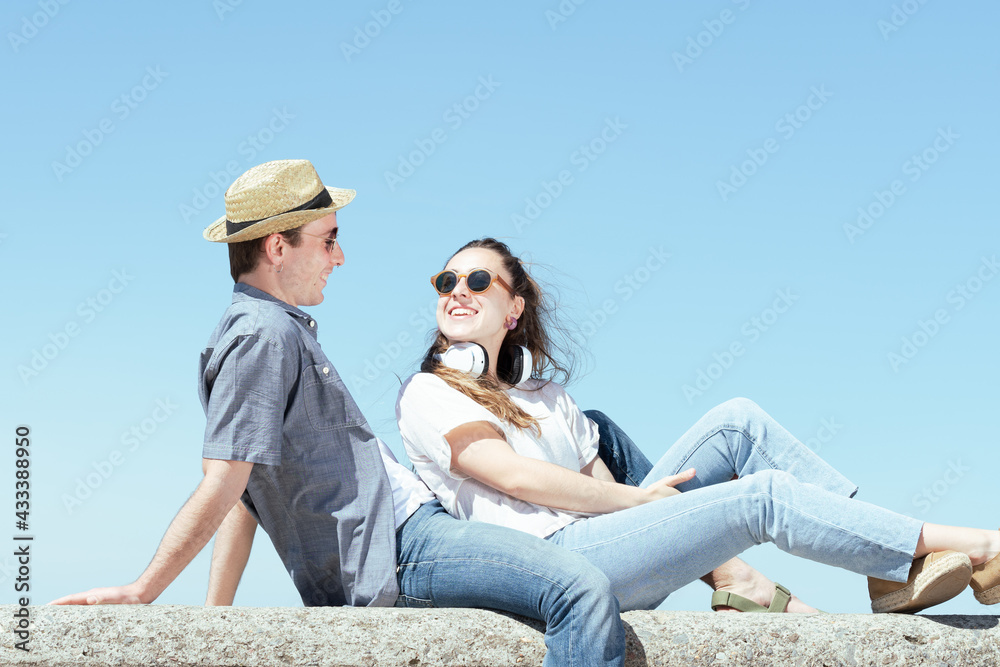 Happy romantic tourist couple sitting on a stone bench and looking each other.