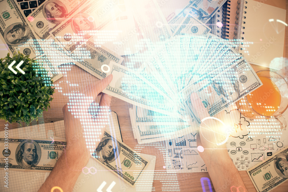 Double exposure of world map drawing hologram and us dollars bills and man hands. Double exposure of world map drawing hologram and us dollars bills and man hands.