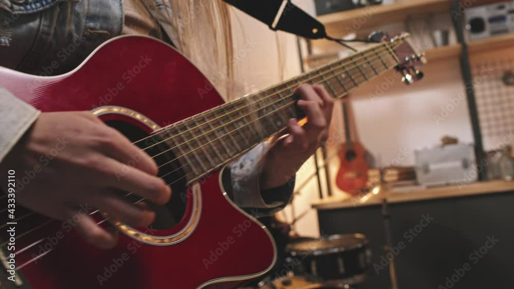Slowmo closeup of rock-n-roll girl energetically playing guitar and drummer girl playing drums in background, performing new song in cozy old-school studio Slowmo closeup of rock-n-roll girl energetically playing guitar and drummer girl playing drums in background, performing new song in cozy old-school studio