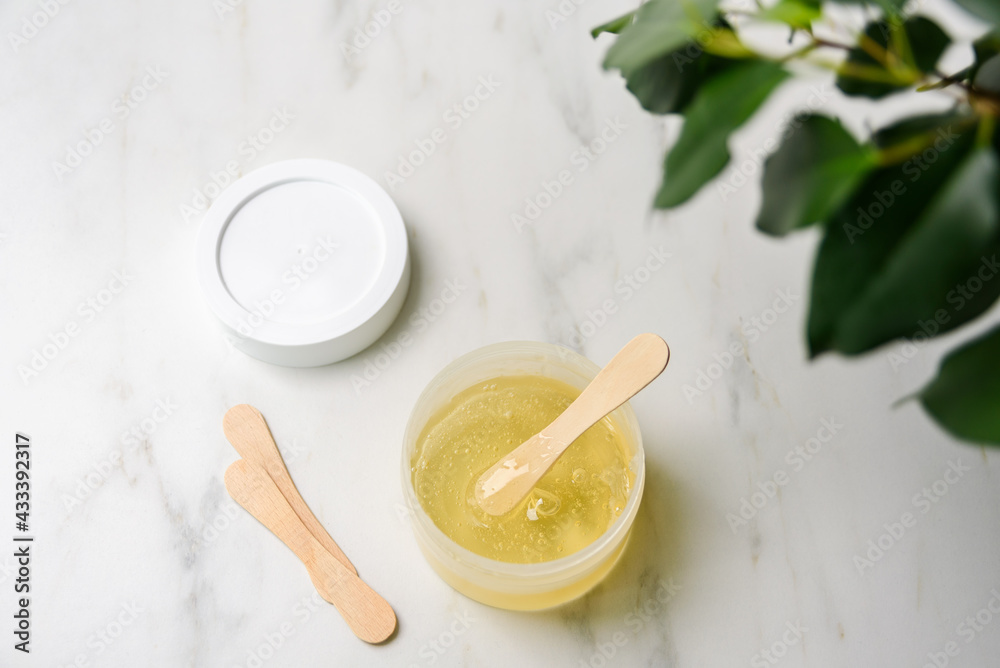 Liquid yellow sugar paste or wax for epilation on wooden stick or spatula closeup Liquid yellow sugar paste or wax for epilation on wooden stick or spatula closeup