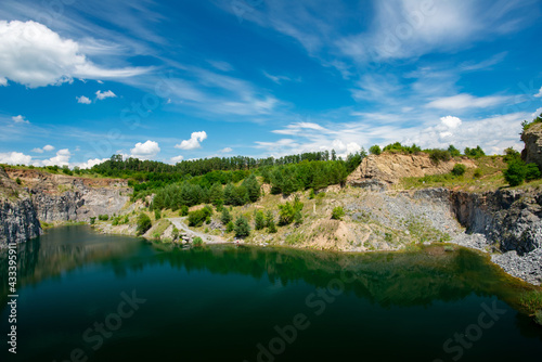 view of the lake and the green vegetation at the base of the rocky mountain