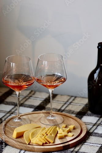 two glasses of wine and cheese with bottle