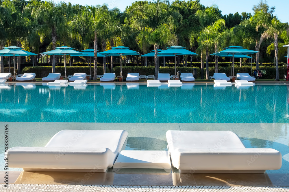 Sunbeds near the pool in a sunny day Sunbeds near the pool in a sunny day