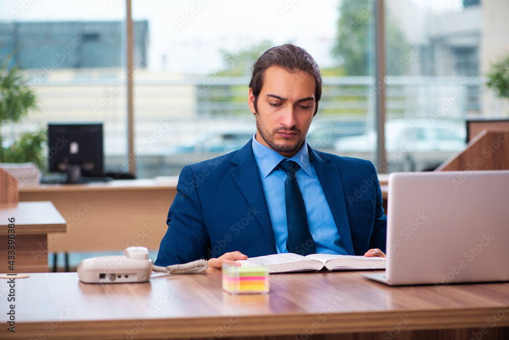 Young male employee reading book in the office Young male employee reading book in the office