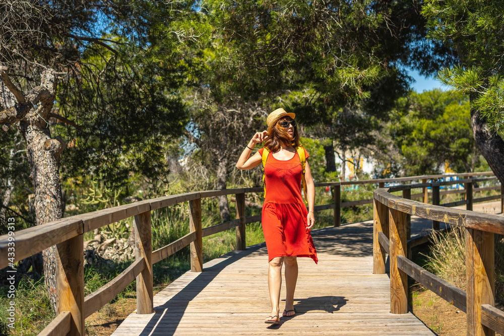 A young tourist woman walking along the wooden walkway towards Moncayo Beach in Guardamar del Segura, Alicante. Community of Valencia. Spain A young tourist woman walking along the wooden walkway towards Moncayo Beach in Guardamar del Segura, Alicante. Community of Valencia. Spain