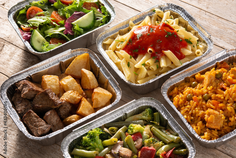 Take away healthy food in foil boxes on wooden table	