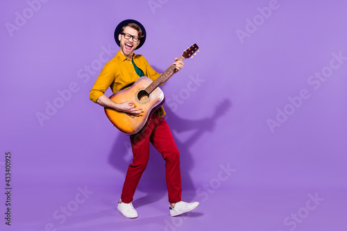 Full length body size view of attractive cheerful crazy guy playing guitar having fun isolated over bright violet purple color background