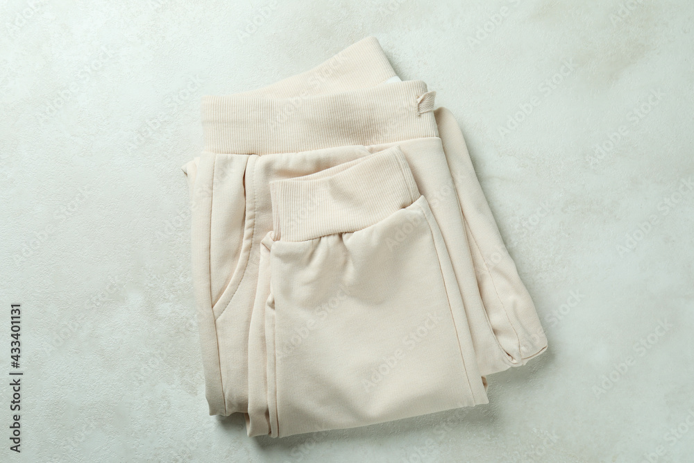 Fototapeta premium Folded sweatpants on white textured background, top view