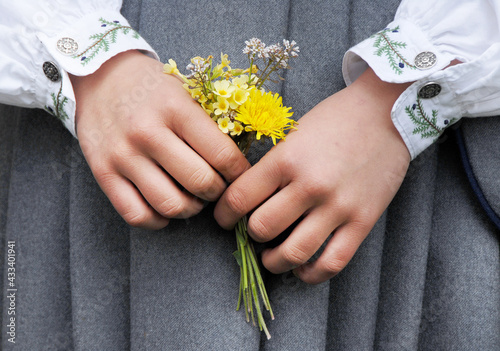 Close up of the hands of a young girl holding a flower bouquet.